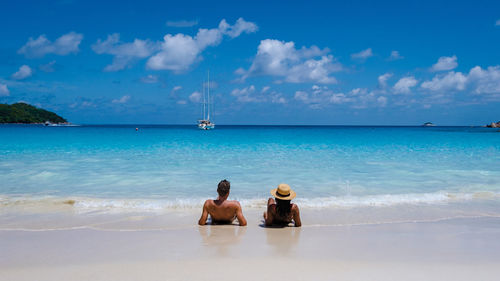 Rear view of woman standing at beach against sky