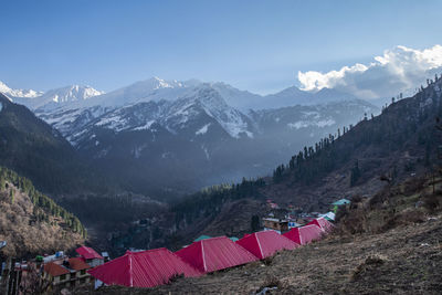 Snow mountain with nice sun rays, clouds and red roof of houses of a village