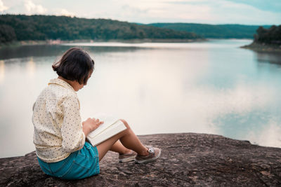 Man sitting on rock looking at lake