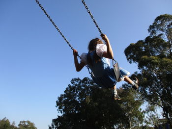 Rear view of girl swinging at park