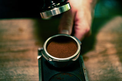 Cropped hands of man holding portafilter by espresso maker