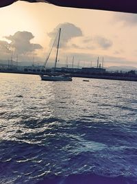 Sailboats in sea against cloudy sky