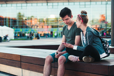 Young man using mobile phone while sitting outdoors