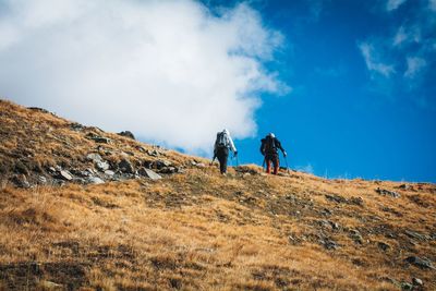 Rear view of man walking on mountain against sky