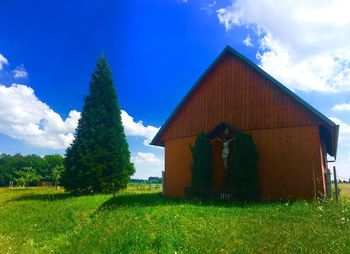 Built structure on field by trees against sky