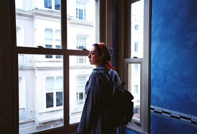 Side view of man looking through window