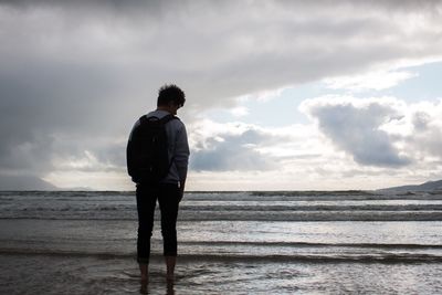 People standing on beach against cloudy sky