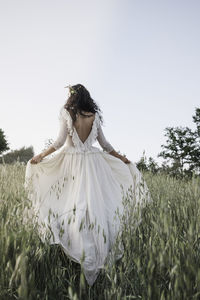 Bride walking in the countryside in a long wedding dress.