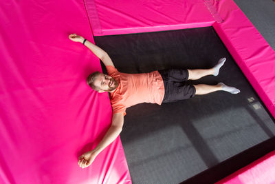 High angle view of woman lying on pink blanket