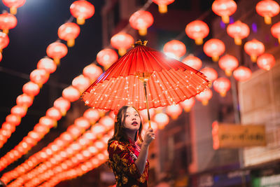 Portrait of woman with red umbrella standing on street