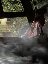 Midsection of woman with umbrella against sky seen through window