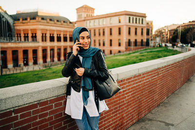 Portrait of young woman standing on mobile phone