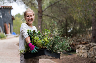 Woman working in the garden carrying plants in the container