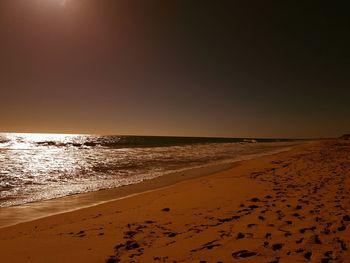 Scenic view of beach against clear sky during sunset