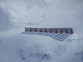 High angle view of snow covered bench on field