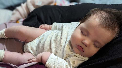 Close-up of cute baby girl lying on bed at home