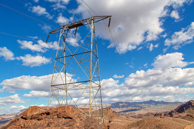 Low angle view of electricity pylon on field against sky