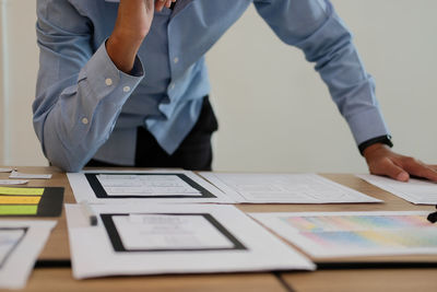 Midsection of businessman with icons on paper at desk