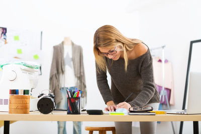 Beautiful female design professional working at workbench in studio