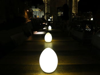 Illuminated lamp on table at night