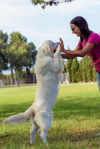 Woman with dog on field against trees 