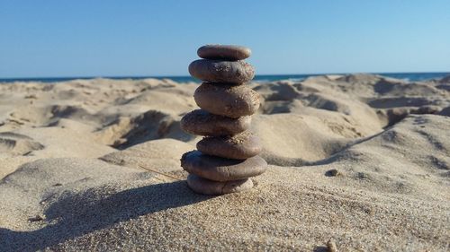 Stack of pebbles on beach against clear sky