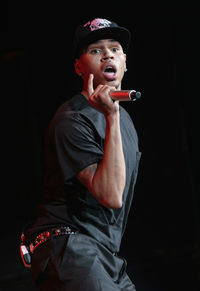 Young man wearing hat while standing against black background