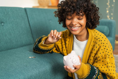 Portrait of young woman using mobile phone while sitting on sofa at home