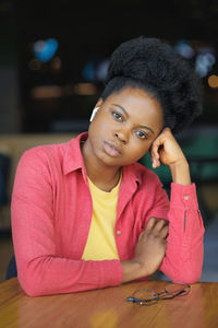 Portrait of young woman sitting on table at home