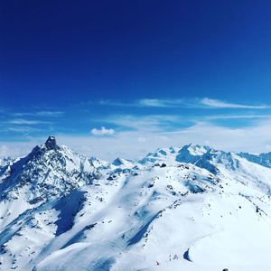 Scenic view of snowcapped mountains against blue sky
