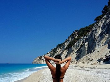 Woman on beach against clear blue sky