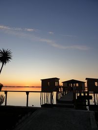 Silhouette pier on beach against sky during sunset