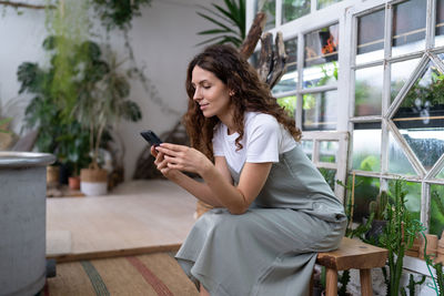 Happy smiling woman relax in home garden using smartphone chatting in social media with friend