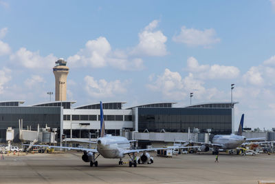 Airplane on airport runway against sky in city