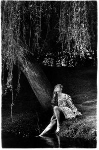 Woman sitting on tree trunk at night