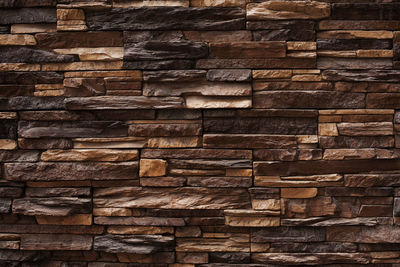 Full frame shot of logs against brick wall