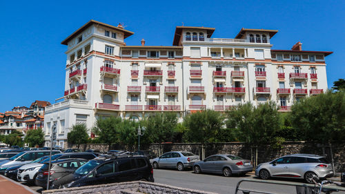 Cars on road by buildings against blue sky