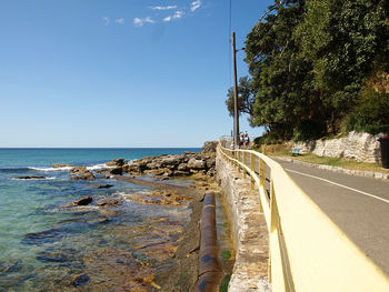 Road by sea against blue sky