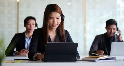 Happy business persons working at laptop at office