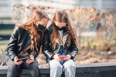 Low section of woman sitting on mobile phone