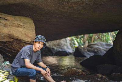 Portrait of young man sitting on rock