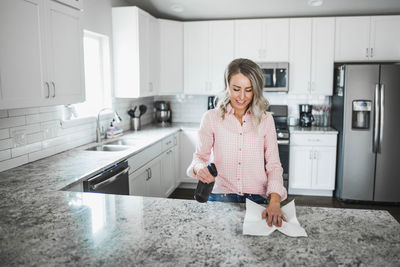 Woman cleaning kitchen counter at home