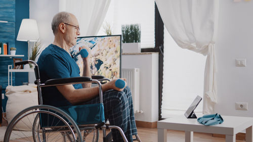 Side view of man using mobile phone at home