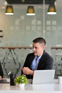 Side view of businessman using laptop while sitting on table