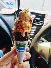 Midsection of person holding ice cream in car