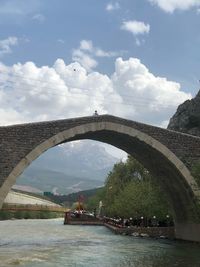 Arch bridge over river against sky