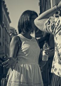 Rear view of woman with arms raised standing outdoors