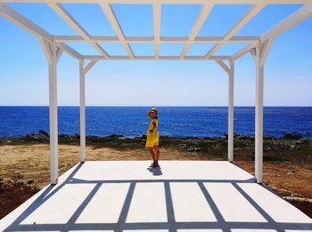 Portrait of woman standing at beach against clear sky