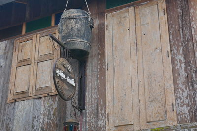 Low angle view of electric lamp hanging on old building