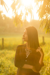 Young woman standing on field against trees